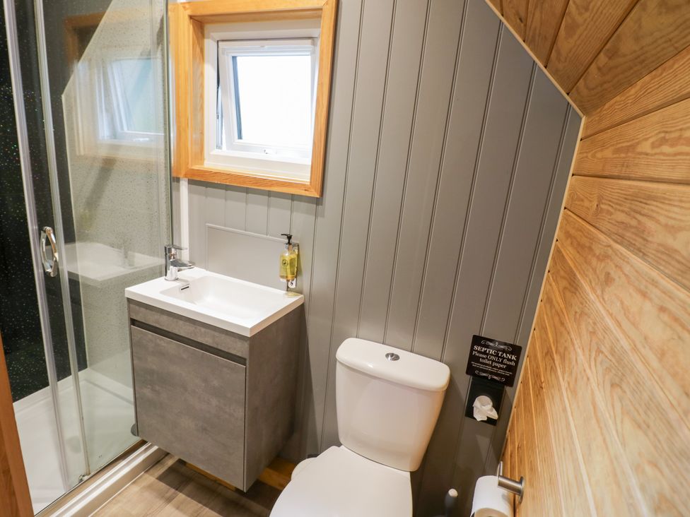 A bathroom with a shower, sink, and toilet at Willow Lodge At Bridge Lake Farm & Fishery in Chacombe