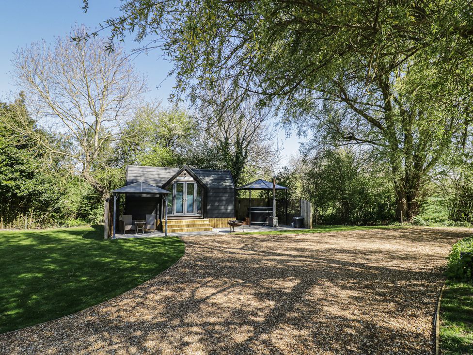 A cabin with a deck and seating area at Willow Lodge At Bridge Lake Farm & Fishery Chacombe