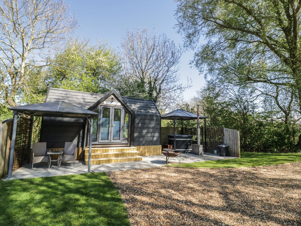A cabin with a terrace and outdoor seating at Willow Lodge At Bridge Lake Farm & Fishery, Chacombe