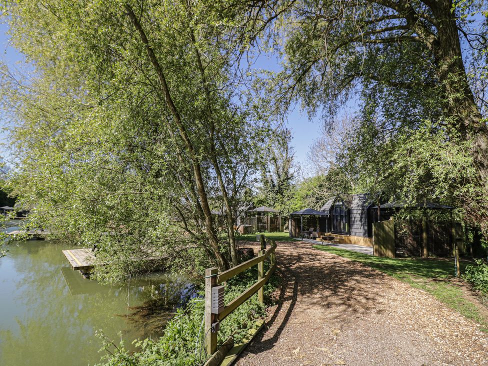 An outdoor path leading to a building by the water at Willow Lodge At Bridge Lake Farm & Fishery Chacombe