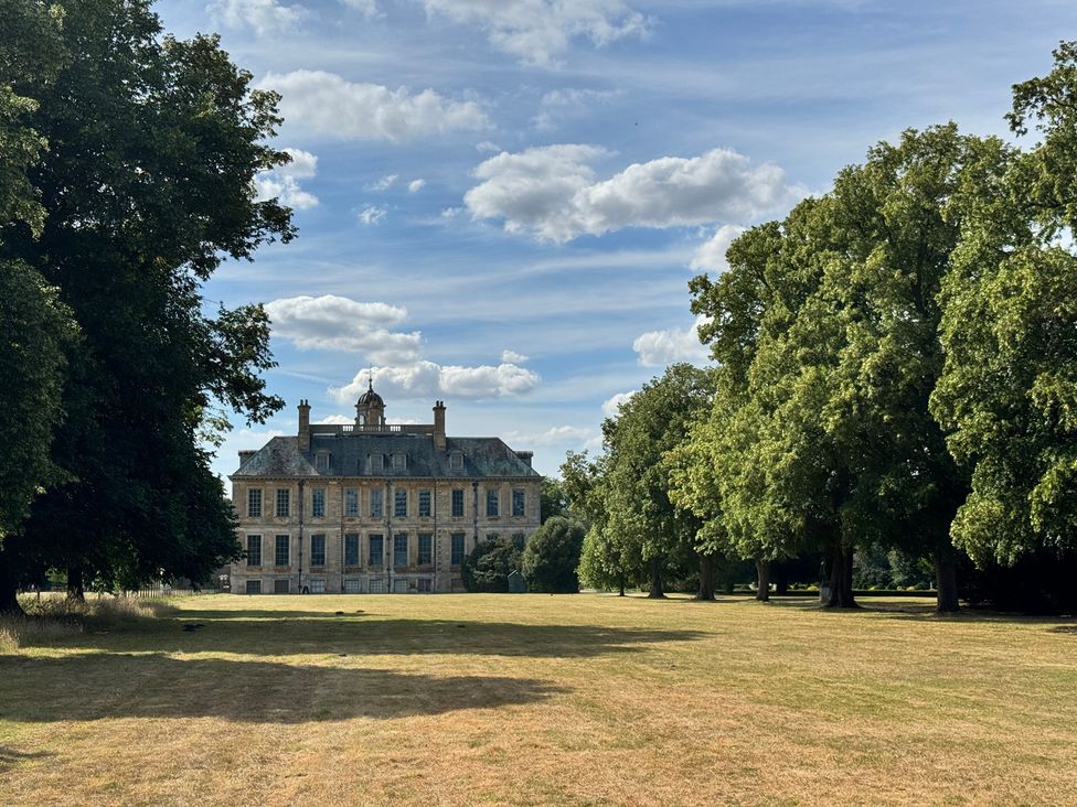 A large building surrounded by trees and grass at Sunny Cottage in Grantham