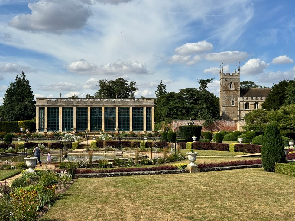 A garden with a greenhouse and a tower at Sunny Cottage in Grantham