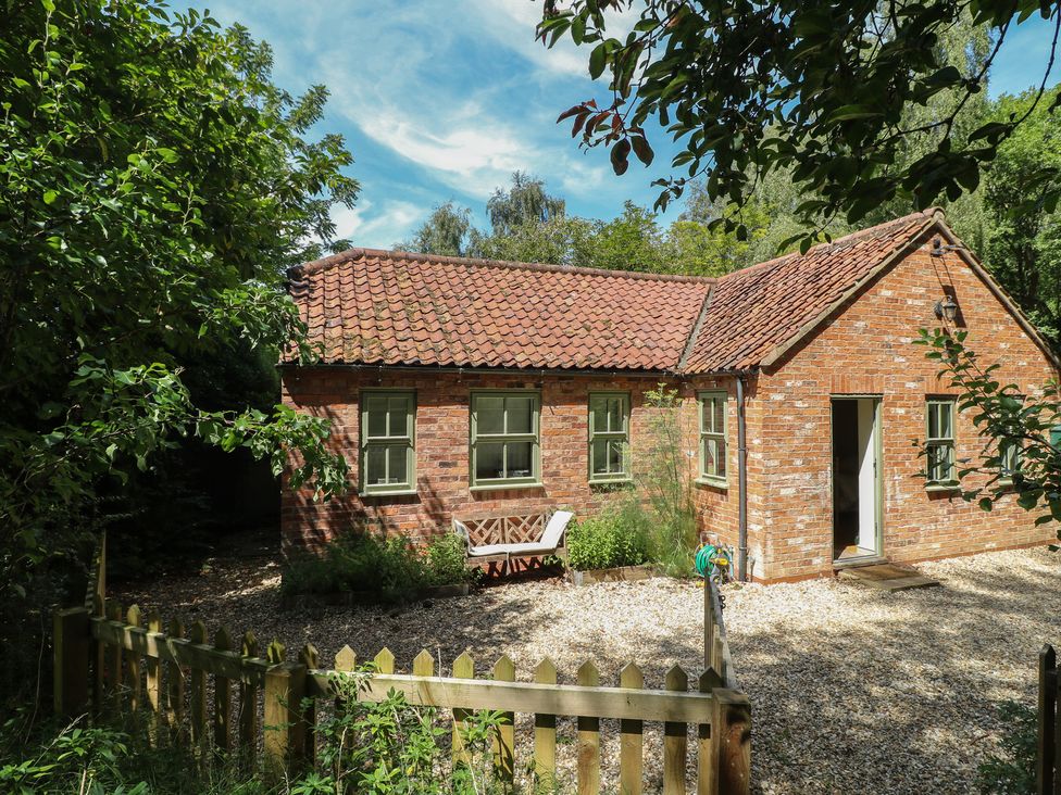 A brick house with a bench and garden at Sunny Cottage in Grantham