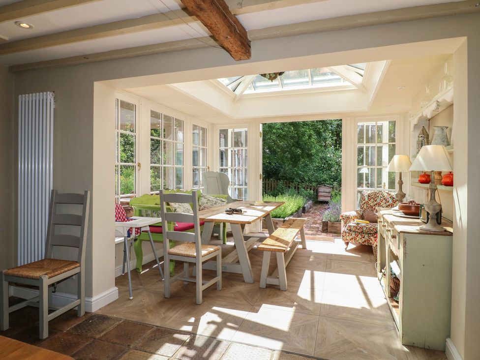 A conservatory with a dining table and chairs at Sunny Cottage in Grantham