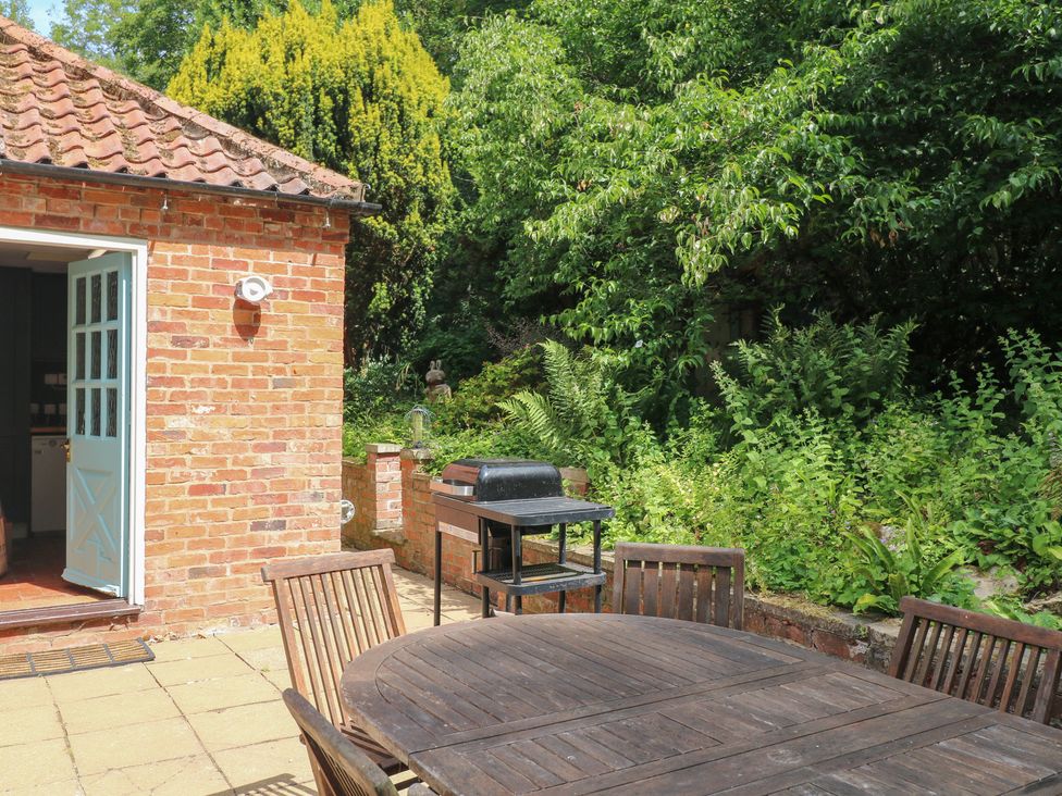 A garden with a table and chairs and a barbecue grill at Sunny Cottage in Grantham