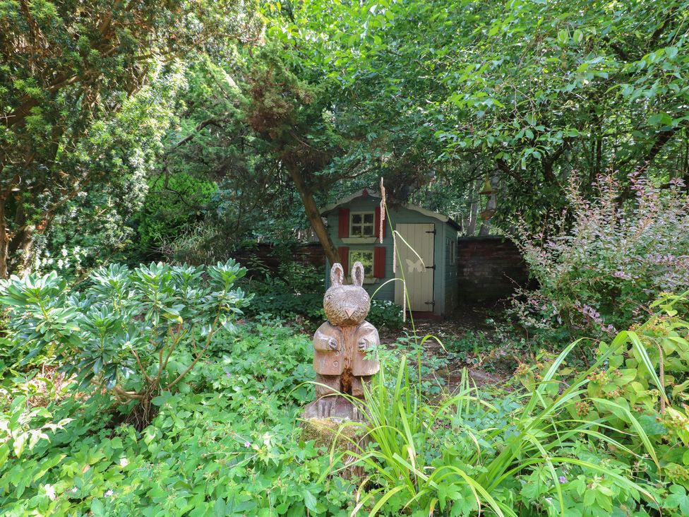 A garden with a wooden rabbit statue and a shed at Sunny Cottage in Grantham
