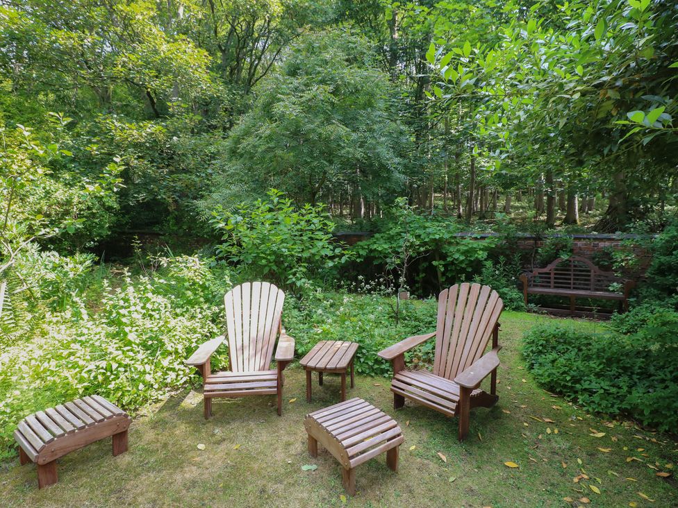 A garden with adirondack chairs and a side table at Sunny Cottage Grantham