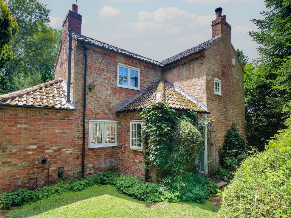 A cottage with a brick exterior and garden at Sunny Cottage in Grantham