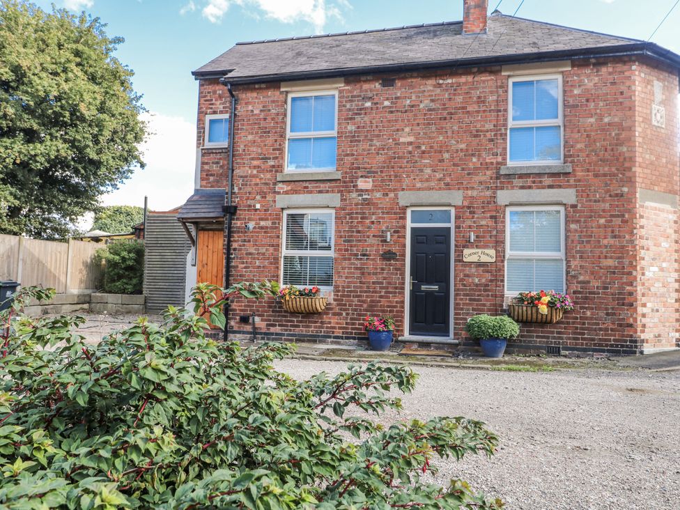 A brick house with flower pots outside at Corner House Cottage in Mapperley Village