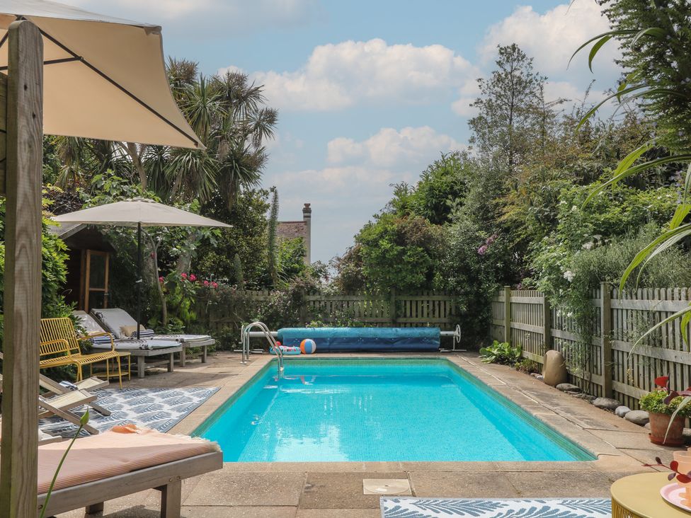 A swimming pool surrounded by deck chairs at Barnsley House in Teignmouth