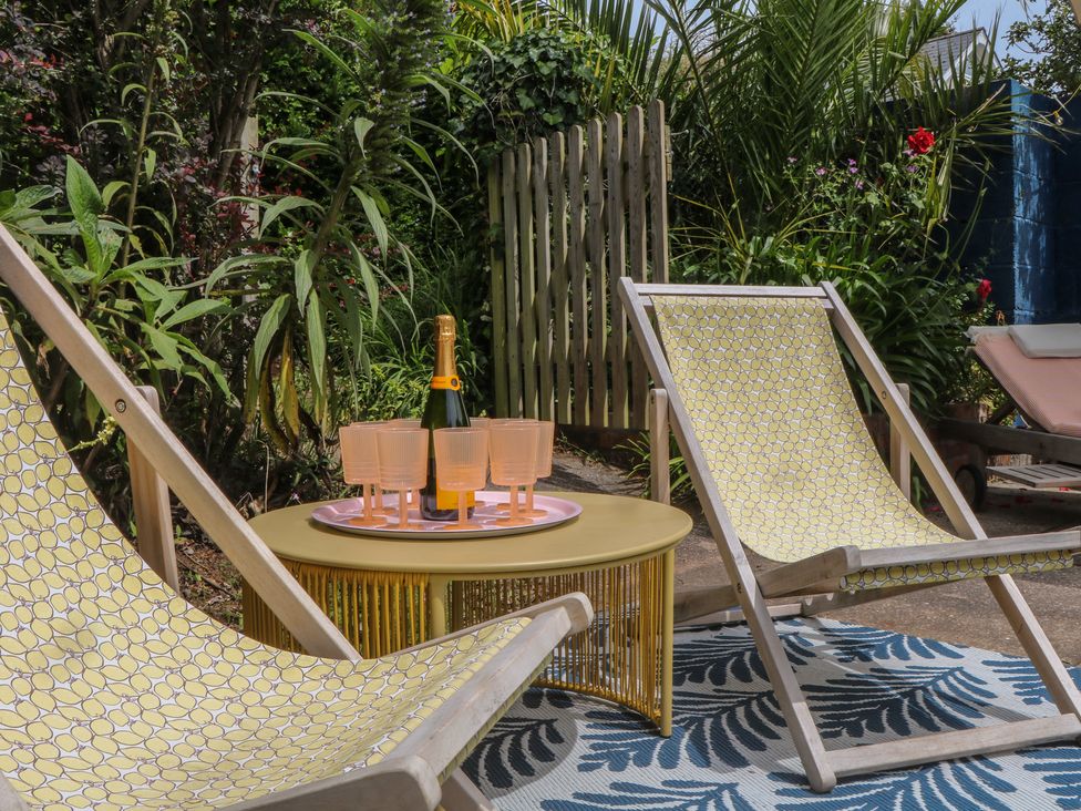 A garden with deck chairs and a table holding champagne at Barnsley House Teignmouth