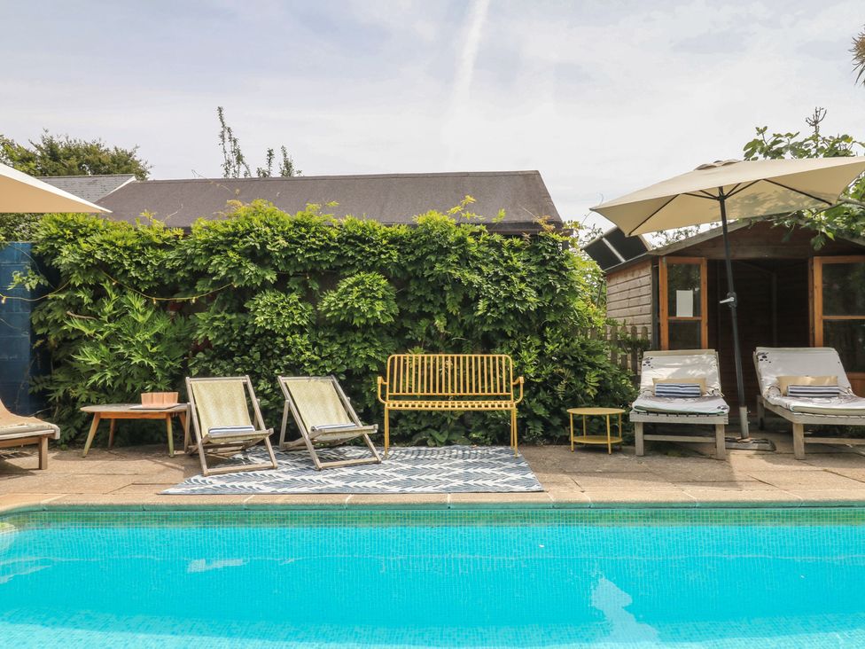 A swimming pool with deck chairs and plants at Barnsley House in Teignmouth