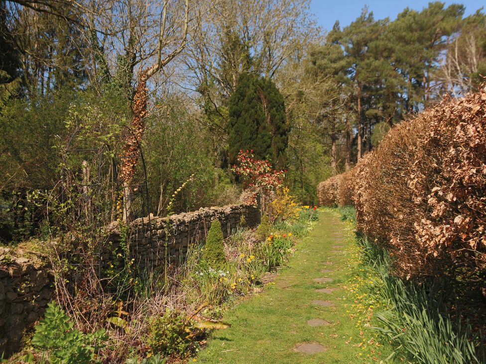 A garden pathway with flowers and stone walls at The Old Bakery South Perrott near Mosterton