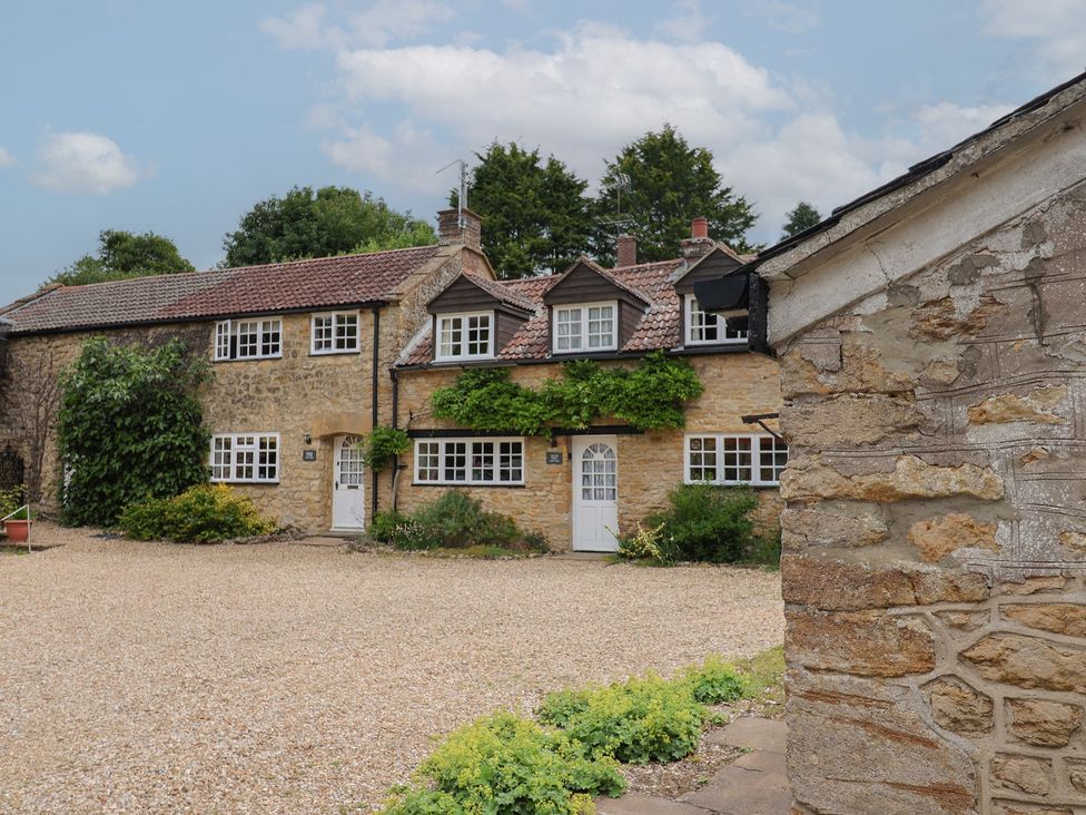 An outdoor view of a cottage with stone walls and gravel at The Old Bakery South Perrott near Mosterton