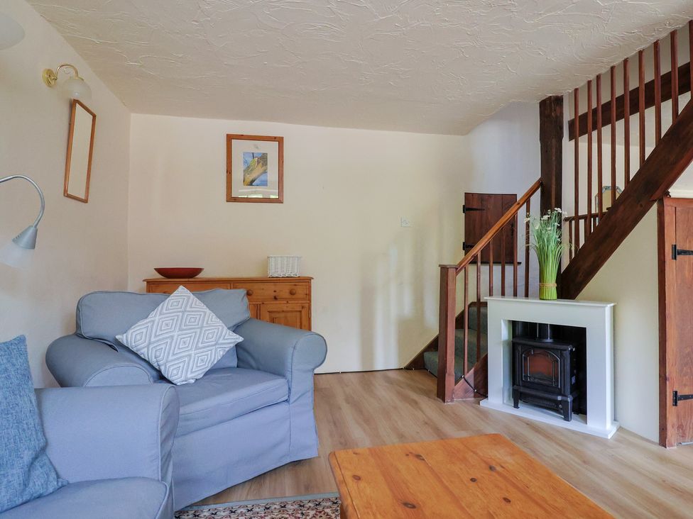 A living room with a sofa, coffee table, and staircase at The Old Bakery in South Perrott near Mosterton