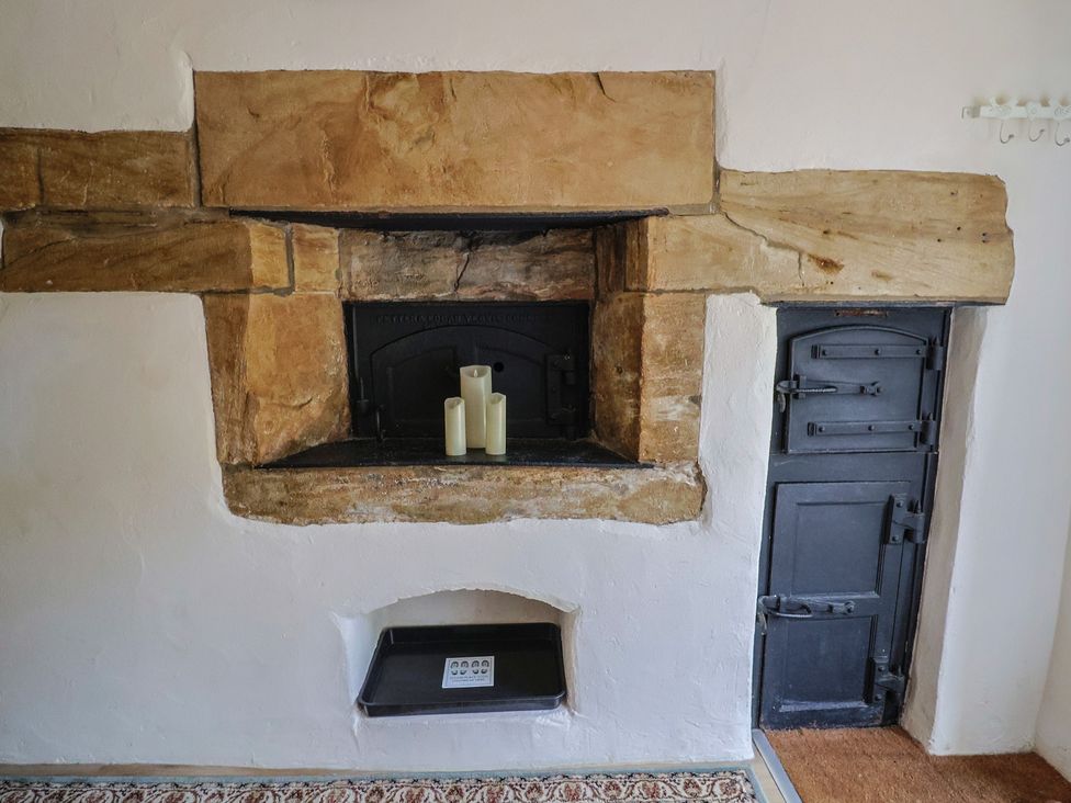 A fireplace with candles and an oven door at The Old Bakery in South Perrott near Mosterton