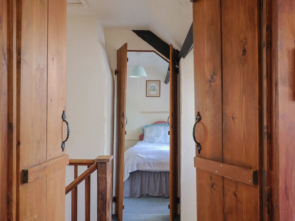 A bedroom entrance with doors and a bed visible at The Old Bakery in South Perrott near Mosterton