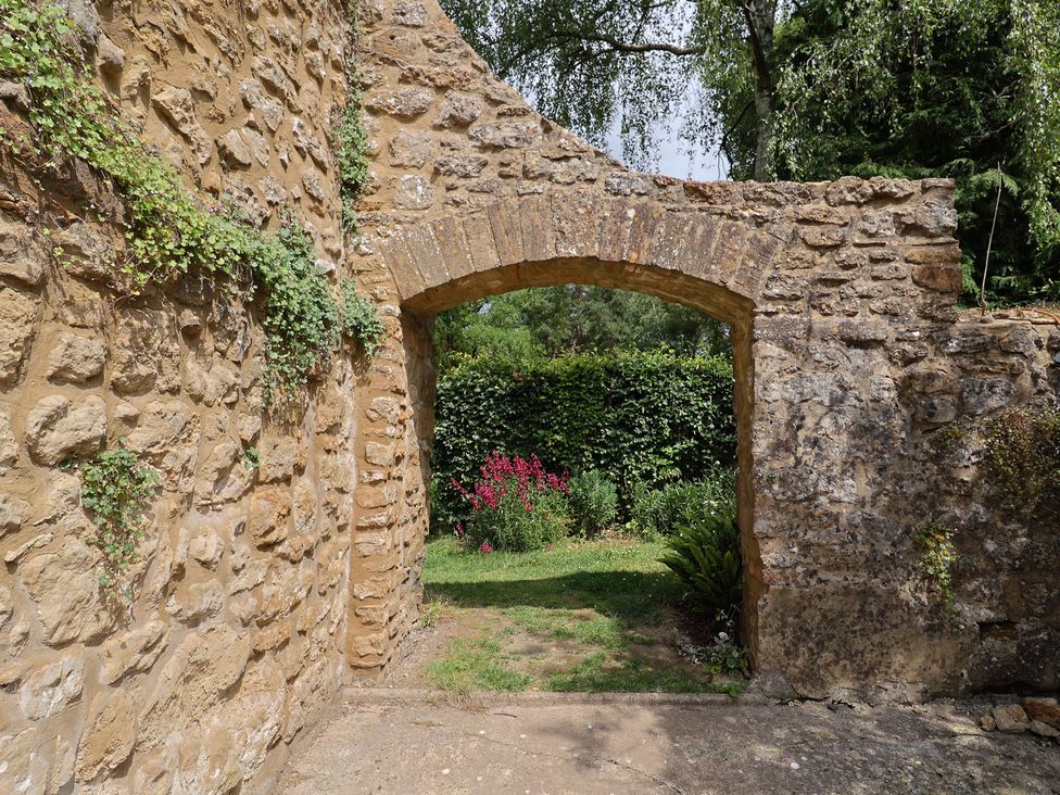 An archway with a stone wall leading to a garden at The Old Bakery South Perrott near Mosterton