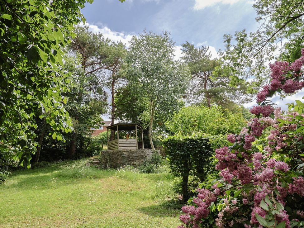 A garden with a gazebo surrounded by trees and flowers at The Old Bakery South Perrott near Mosterton