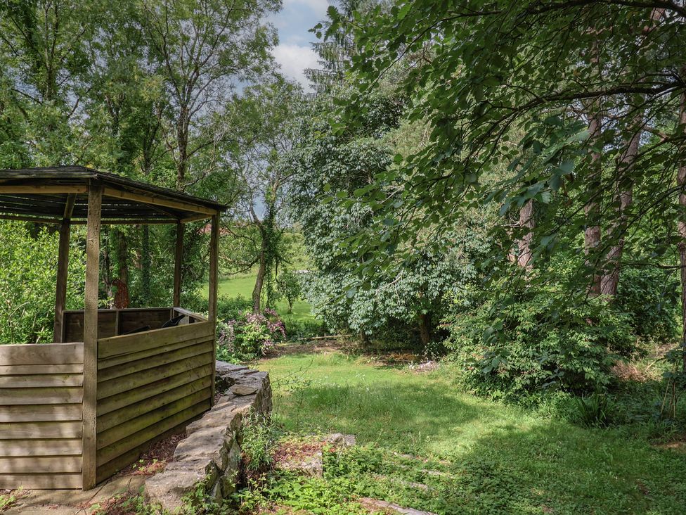 A garden with a wooden gazebo and stone wall at The Old Bakery in South Perrott near Mosterton