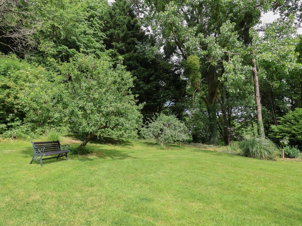 A garden with a bench and trees at The Old Bakery South Perrott near Mosterton