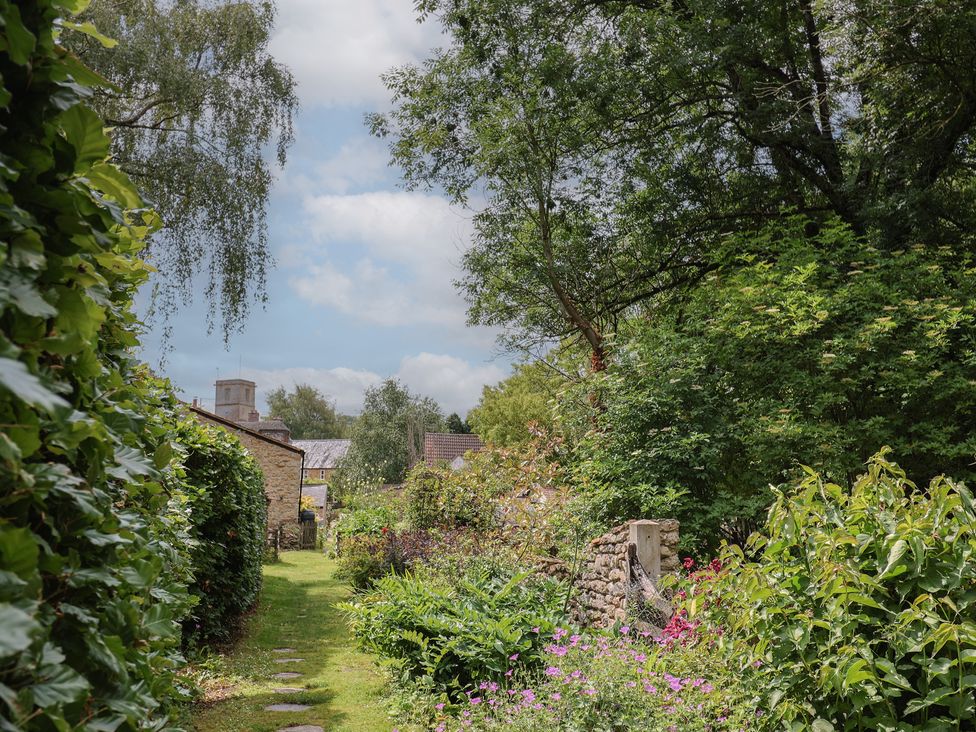 A garden path with flowers and trees at The Old Bakery South Perrott near Mosterton