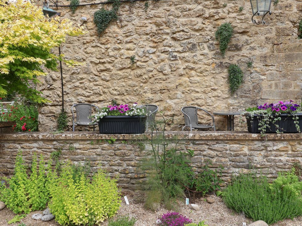 A garden with stone wall, plants, table and chairs at The Old Bakery in South Perrott near Mosterton