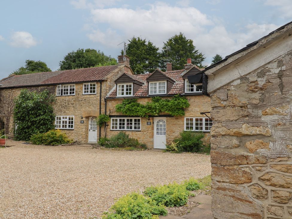 A stone house with a gravel driveway and plants at The Old Bakery South Perrott near Mosterton