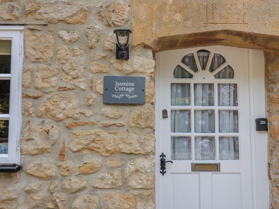 The exterior wall with a door and sign at Jasmine Cottage South Perrott near Mosterton