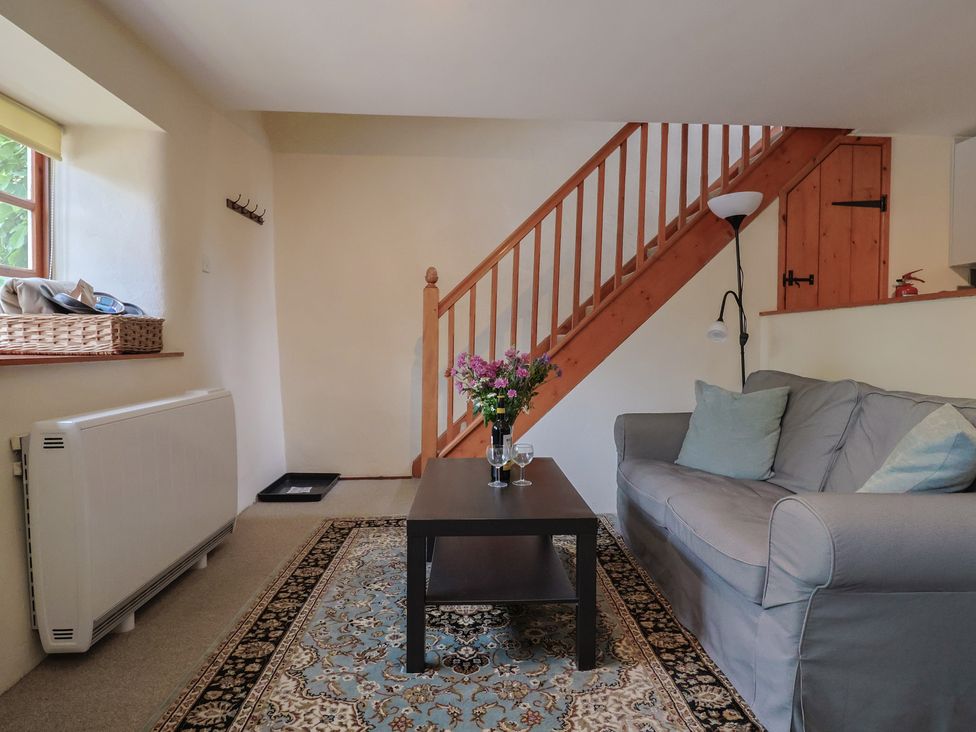 A living room with a sofa, coffee table, and staircase at Jasmine Cottage, South Perrott near Mosterton