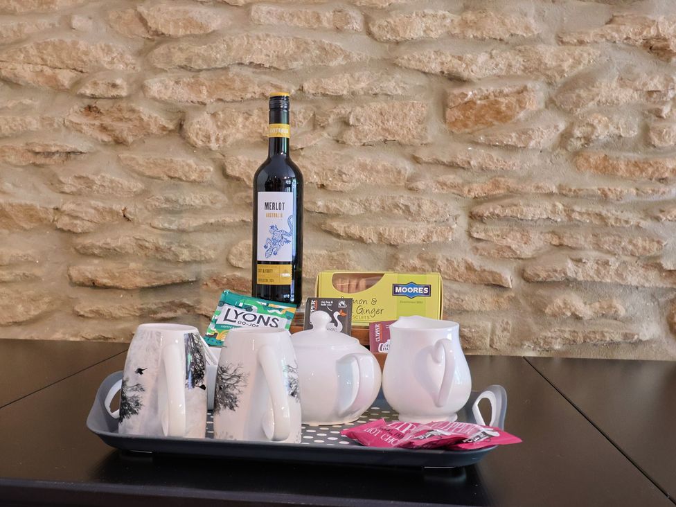 A tray with mugs, a wine bottle, milk jug, tea bags, and biscuits at Jasmine Cottage South Perrott near Mosterton