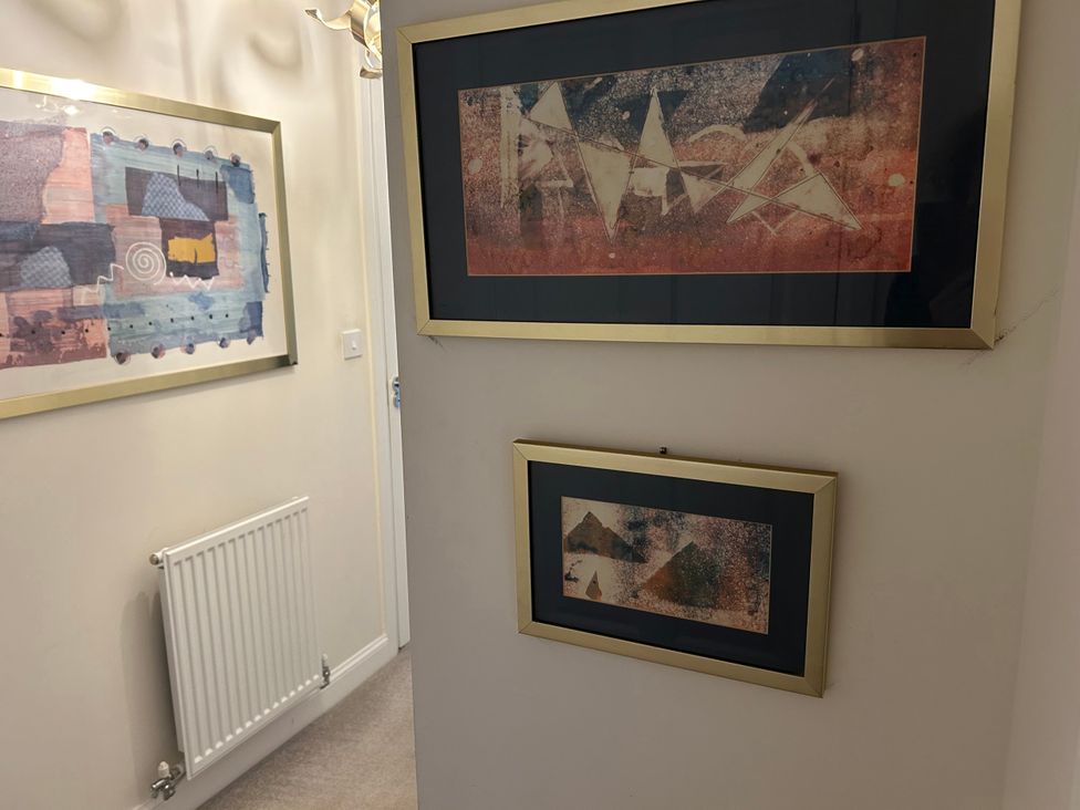 A hallway with framed paintings and a radiator at The Green in Whitby