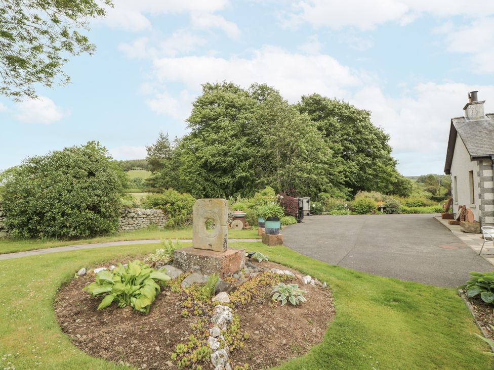An outdoor garden area with a stone sculpture and plants at Torview House Lyne Station near Peebles