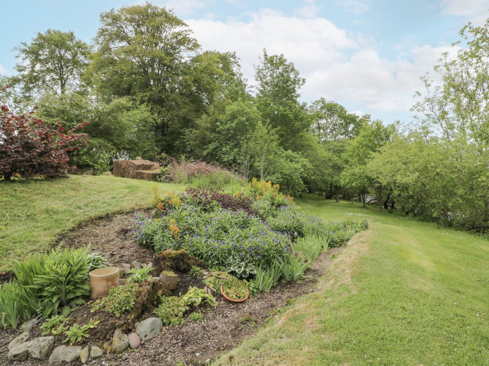 A garden with a flower bed and trees at Torview House Lyne Station near Peebles