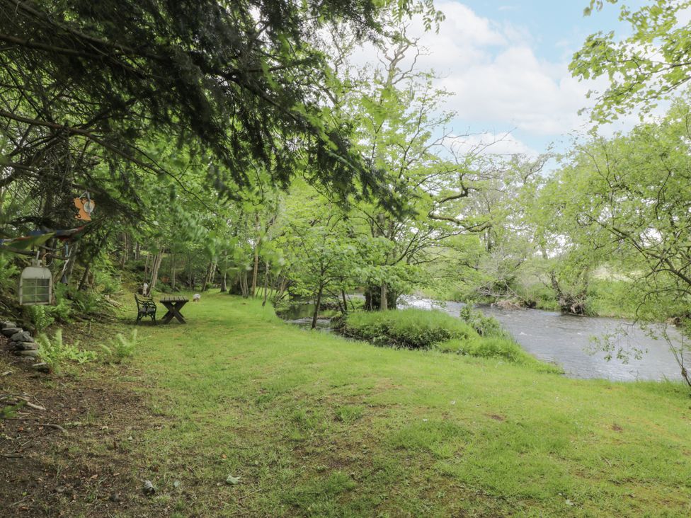 A garden with a table and bench by a river at Torview House in Lyne Station near Peebles