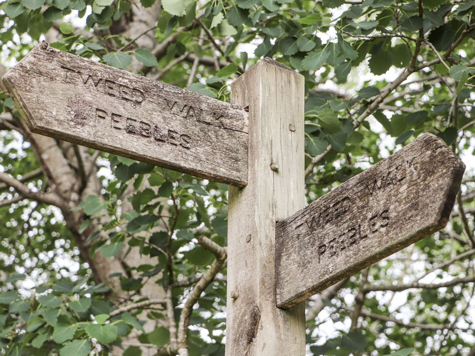 A directional wooden signpost indicating Tweed Walk and Peebles