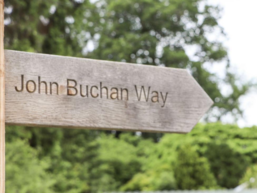 A sign pointing to John Buchan Way in a garden setting near Lyne Station near Peebles