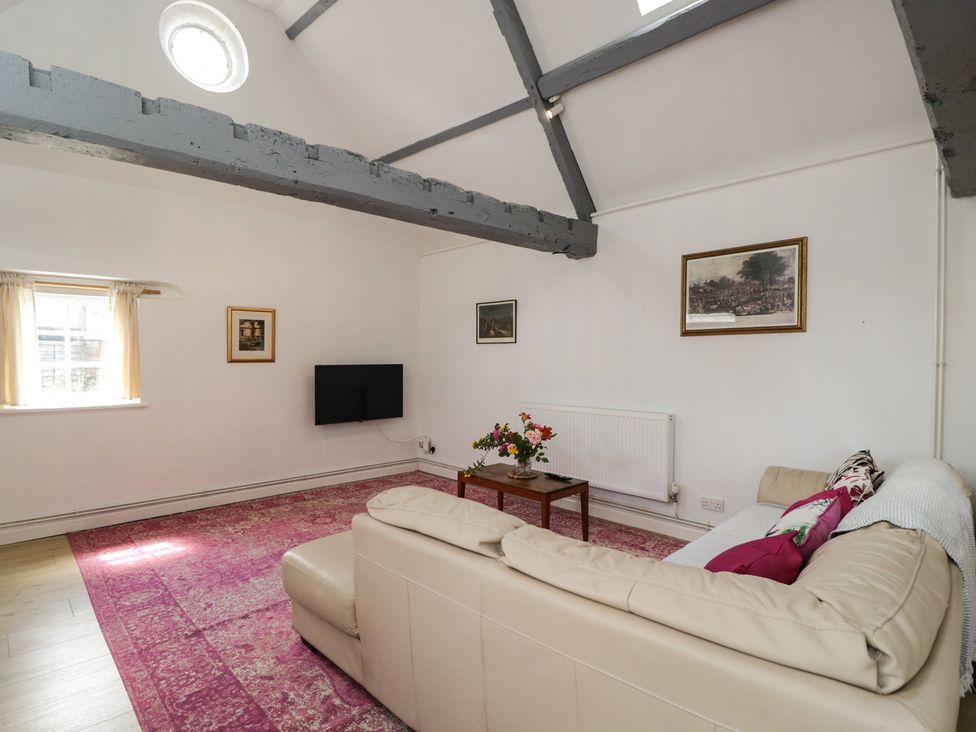 A living room with a sofa and television at Coach House in Swindon