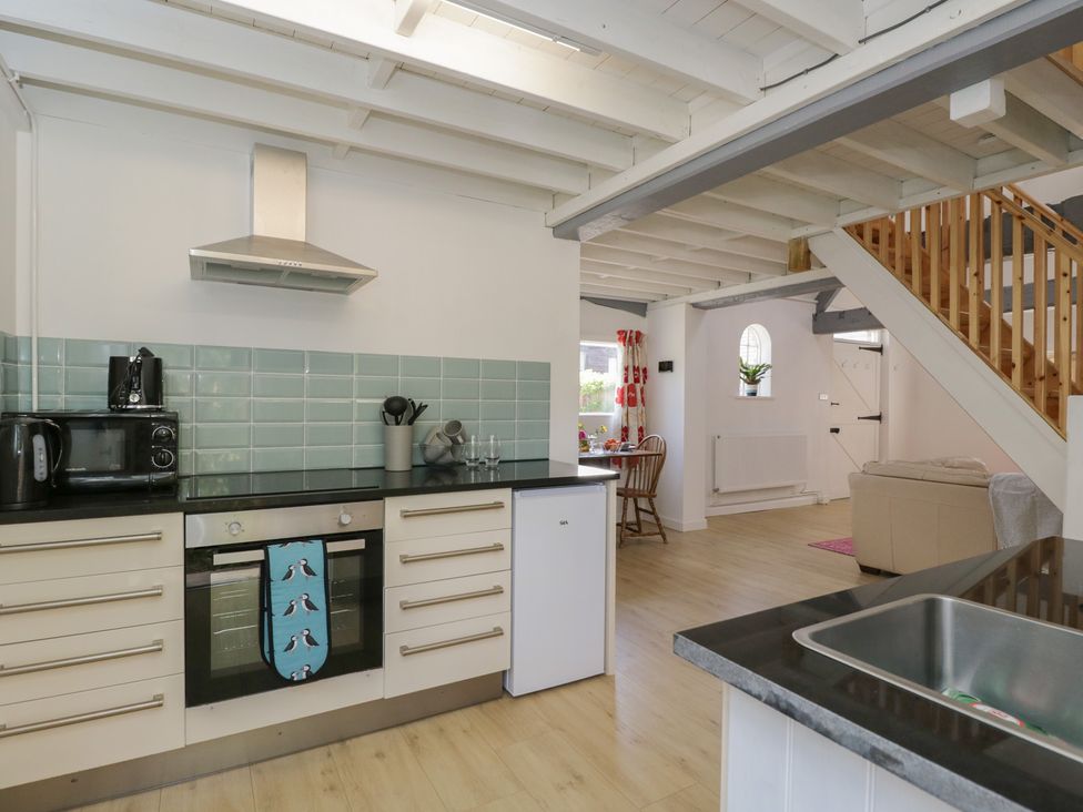A kitchen with appliances and a staircase at Coach House in Swindon