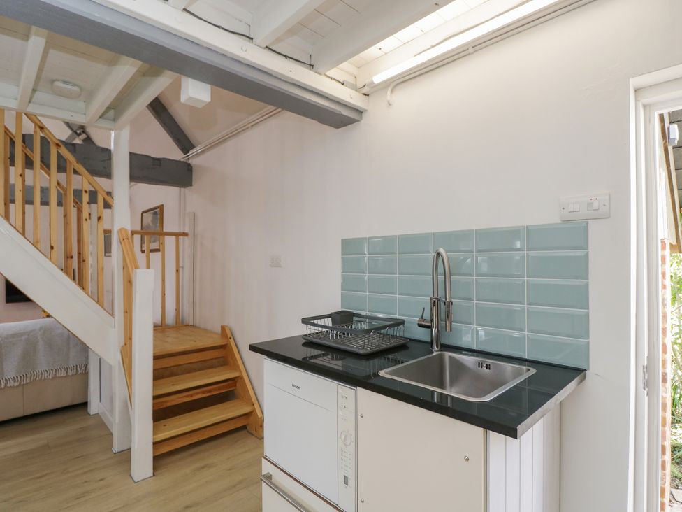 A kitchen area with a sink and staircase at Coach House in Swindon