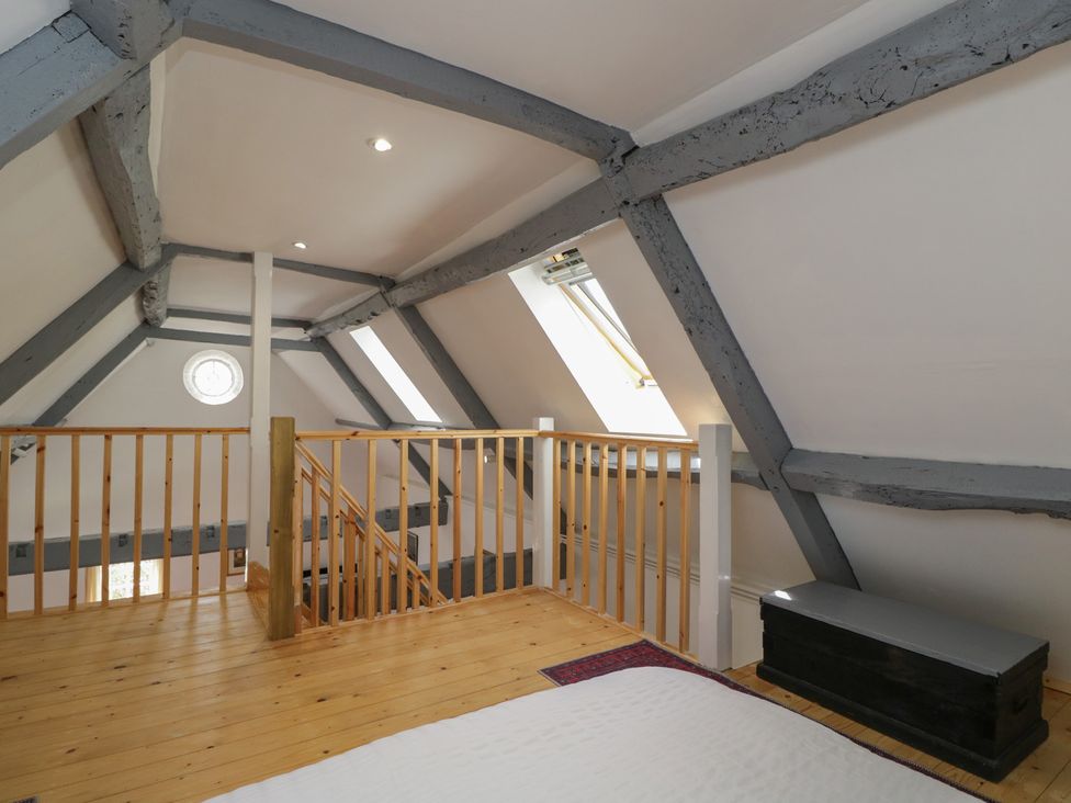 A loft space with wooden beams and railing at Coach House in Swindon