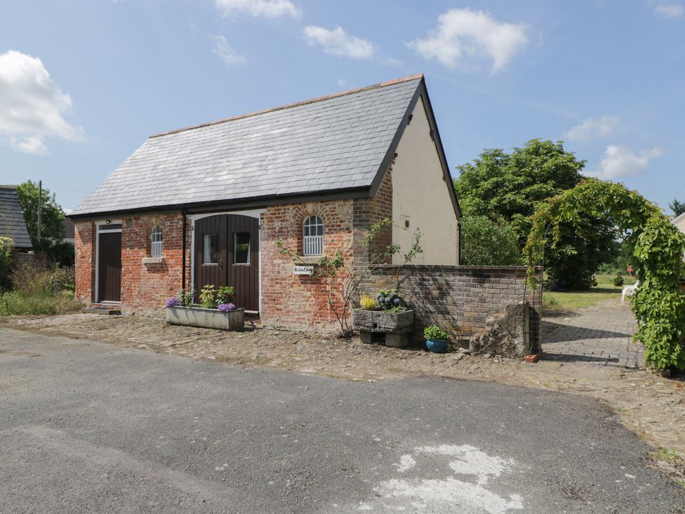 A cottage exterior with a brick wall and pathway at Coach House in Swindon