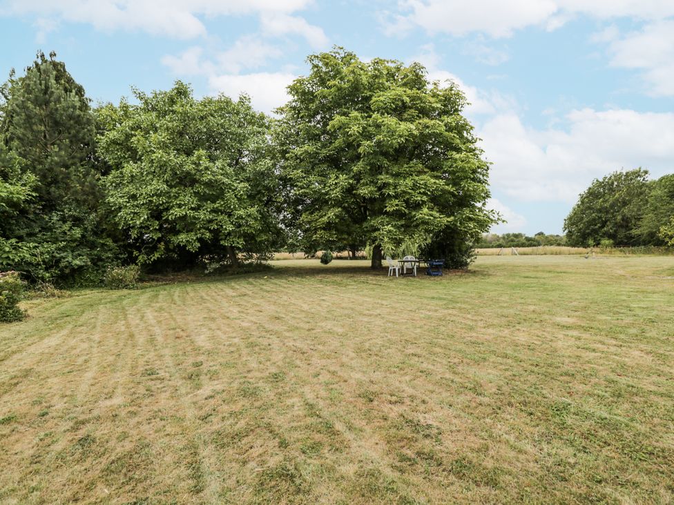 A garden with trees and seating area at Coach House in Royal Wootton Bassett