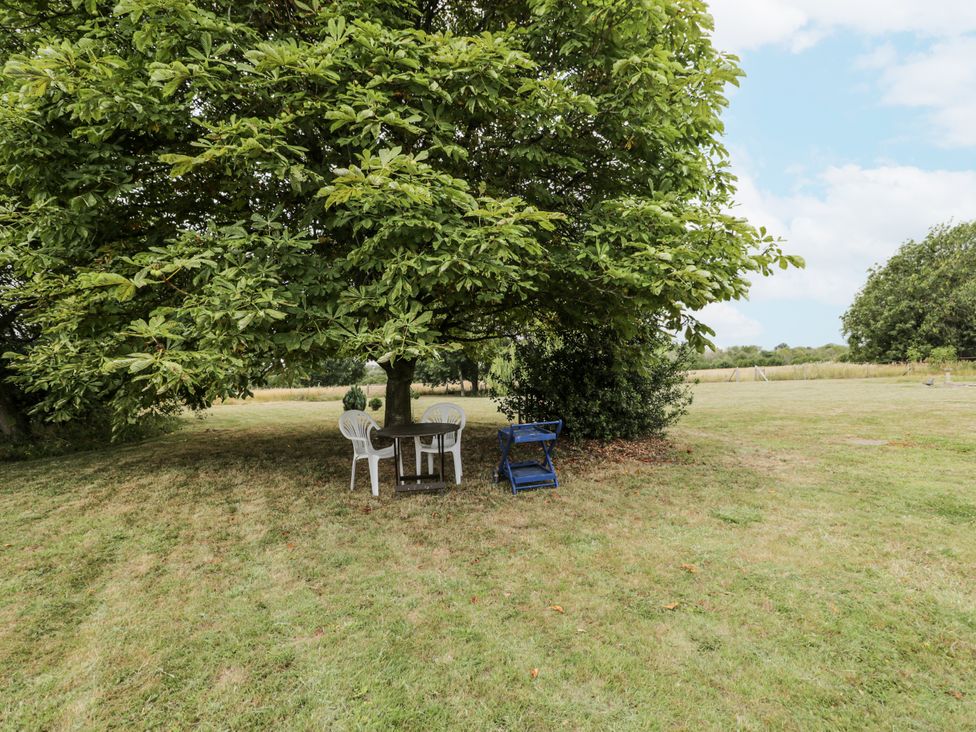 A table and chairs under a tree at Coach House in Royal Wootton Bassett