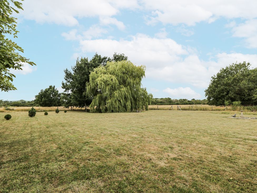 A garden with a willow tree and grassy area at Coach House in Royal Wootton Bassett