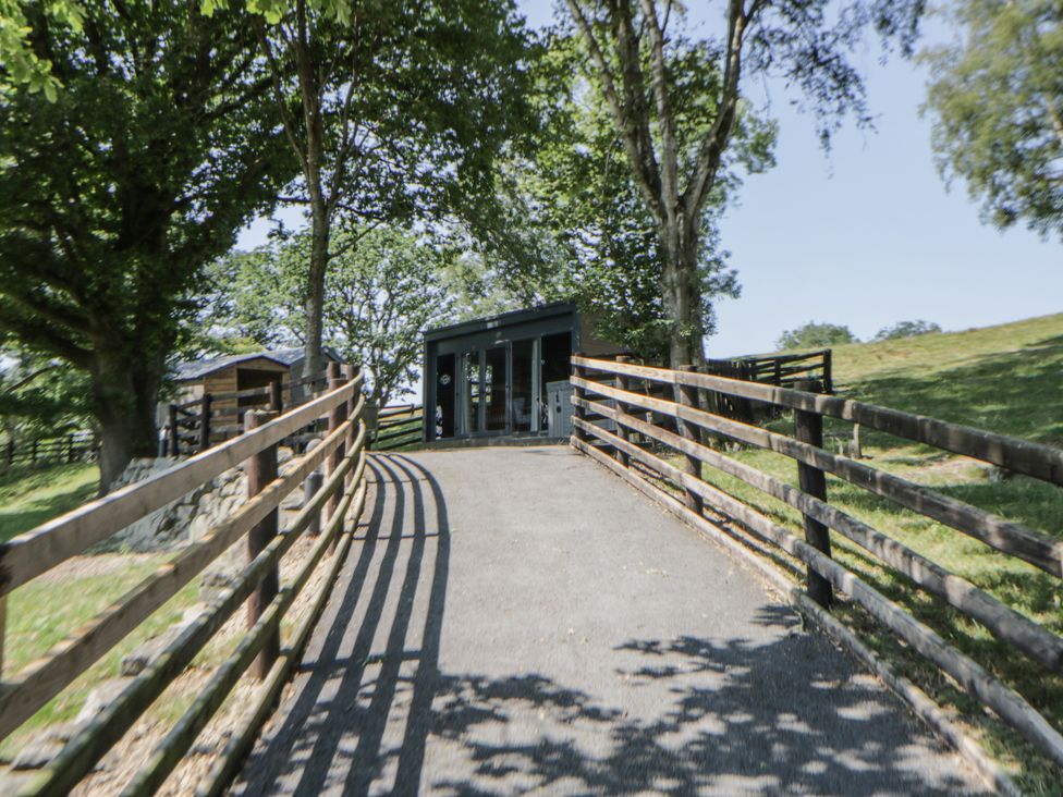A pathway leading to a building surrounded by trees at The Fox Den in Nantmel near Rhayader