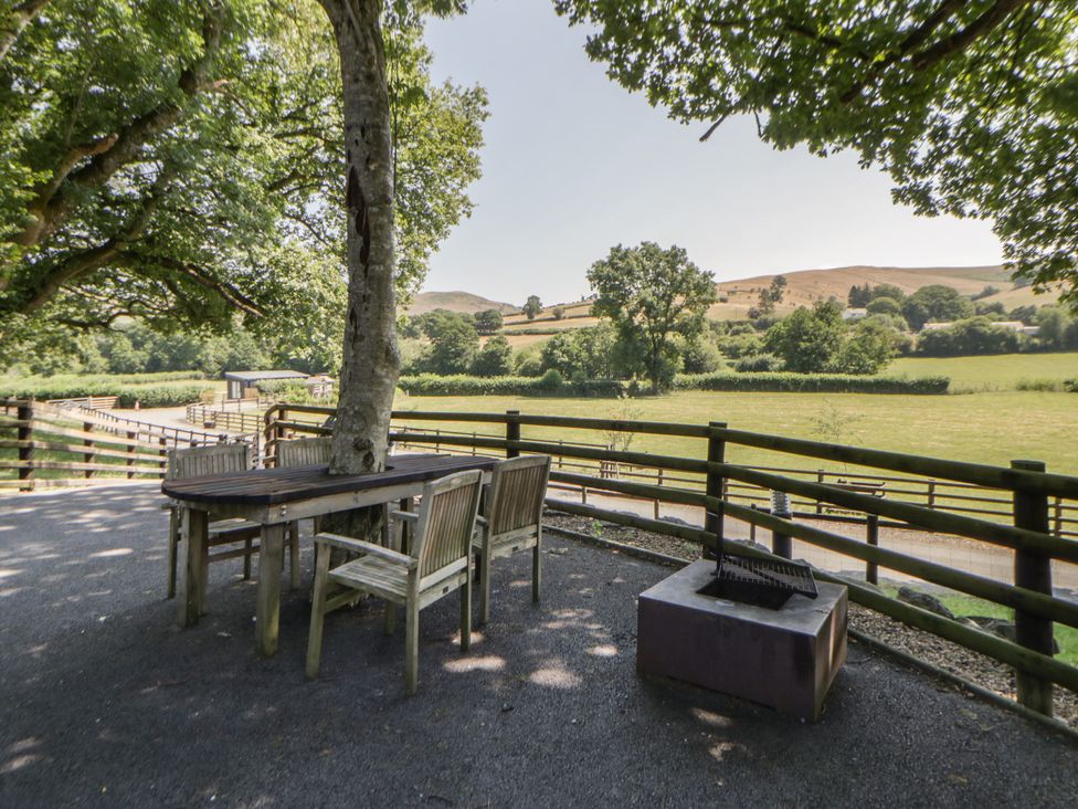 An outdoor area with a table and chairs near a fire pit at The Fox Den Nantmel near Rhayader