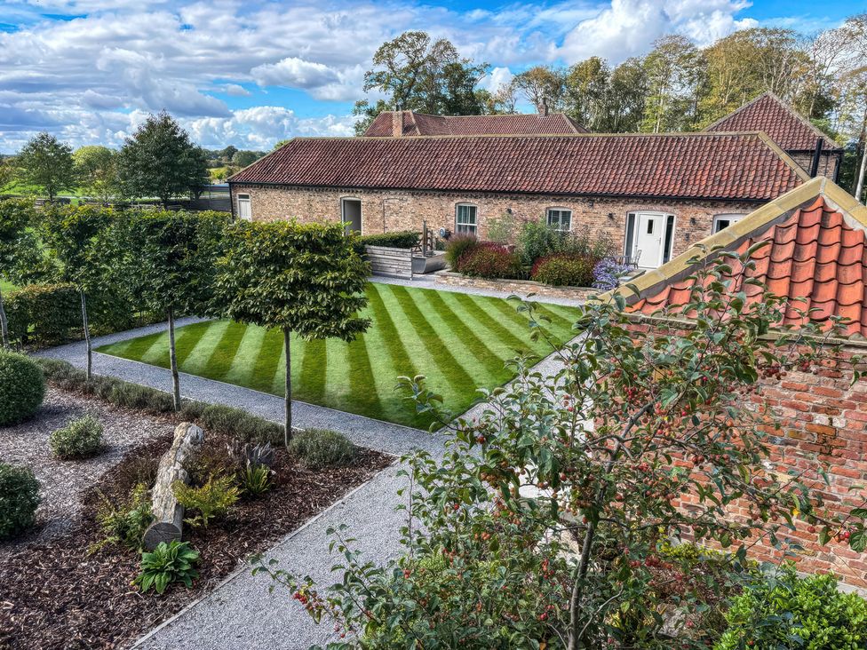 A garden with grass and trees at Flittermouse Barn in Hornsea