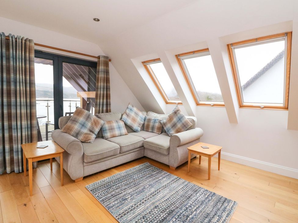 A living room with a sofa and windows at The Apartment in Ardgour