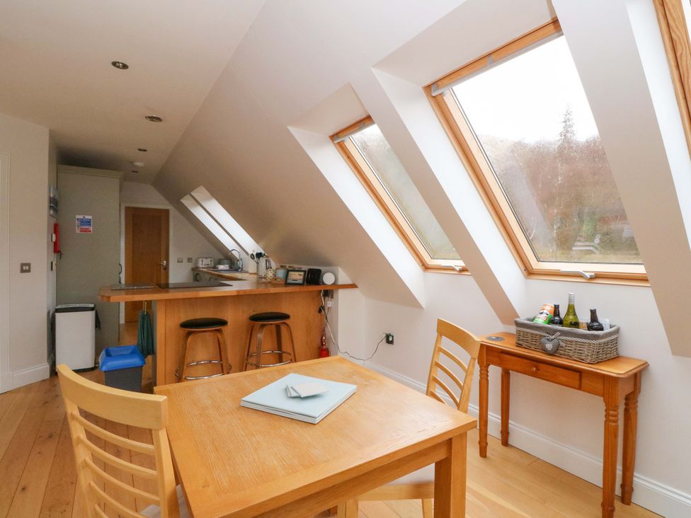 A kitchen with a table and bar stools at The Apartment in Ardgour